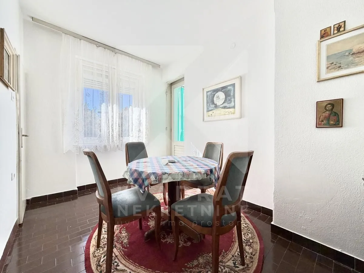 Dining area with a table, four chairs and a rug.