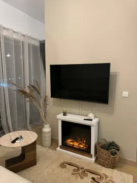 Living room with a TV, electric fireplace, and coffee table. - image 5