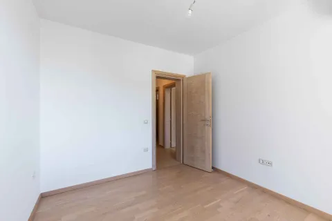 Prazna soba sa bijelim zidovima, drvenim podom i otvorenim drvenim vratima. - image 3