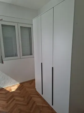 Svijetla soba sa bijelim ormarom i drvenim parketom. - image 8