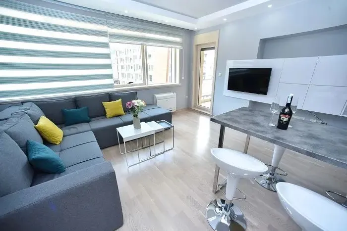 Living room with a sectional sofa, dining table, and a large window.
