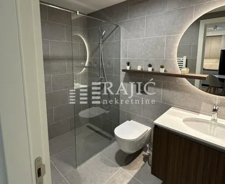 Modern bathroom equipped with a walk-in shower and grey tiling. - image 14