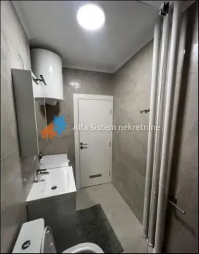 Smaller bathroom with a washbasin, toilet, water heater, and tiled walls. - image 11