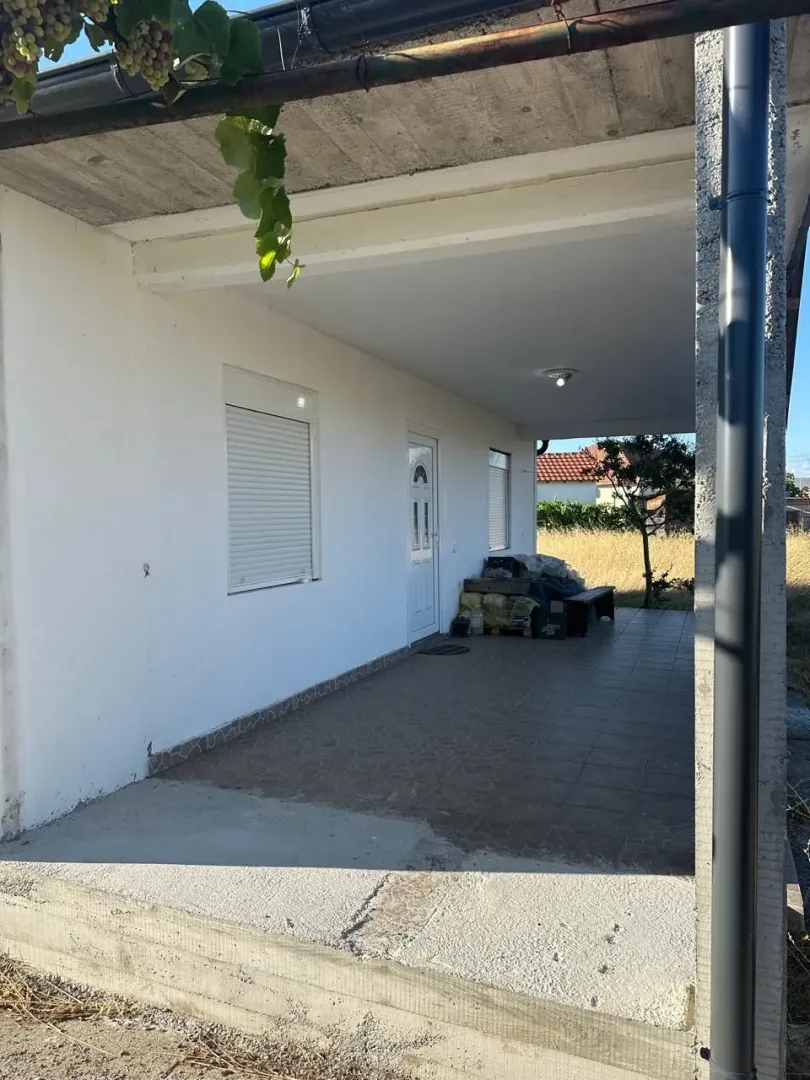 Covered terrace and house entrance with tiled flooring.