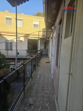 Dugački spoljni hodnik sa popločanim podom i ogradom duž zgrade. - image 5