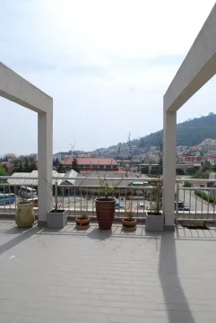 Spacious terrace with potted plants and a view of the city and surrounding hills. - image 9