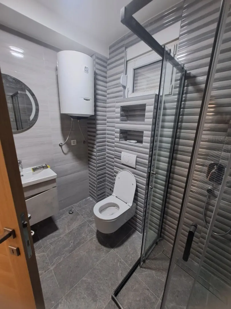 Modernly equipped bathroom with a shower cabin, sink, and toilet.