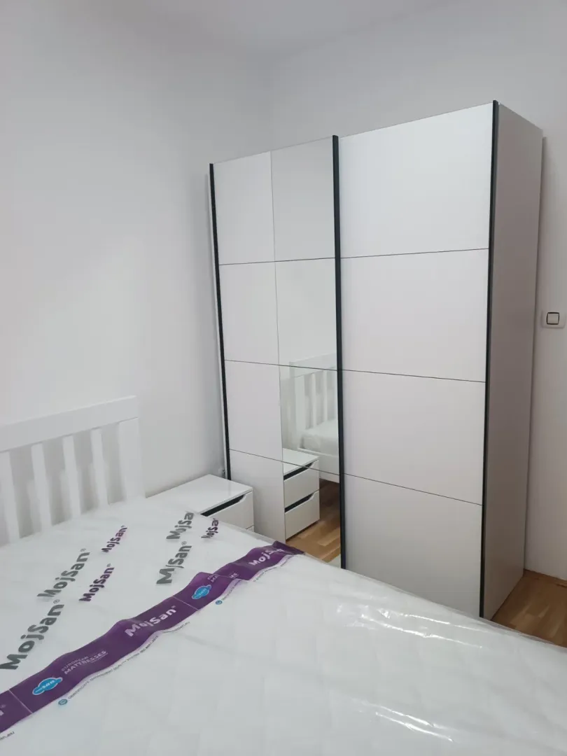 Bright bedroom with a bed and a white wardrobe.