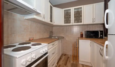 Compact kitchen with white cabinets, a stove, and a microwave. - image 2