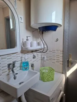 Smaller bathroom with a washbasin, water heater, and washing machine. - image 10