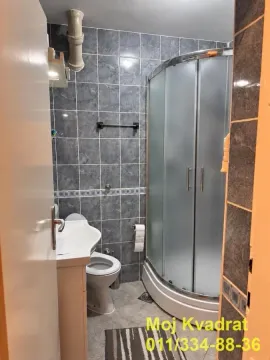 Small bathroom with a shower cabin, washbasin, and toilet tiled with grey-blue tiles. - image 13