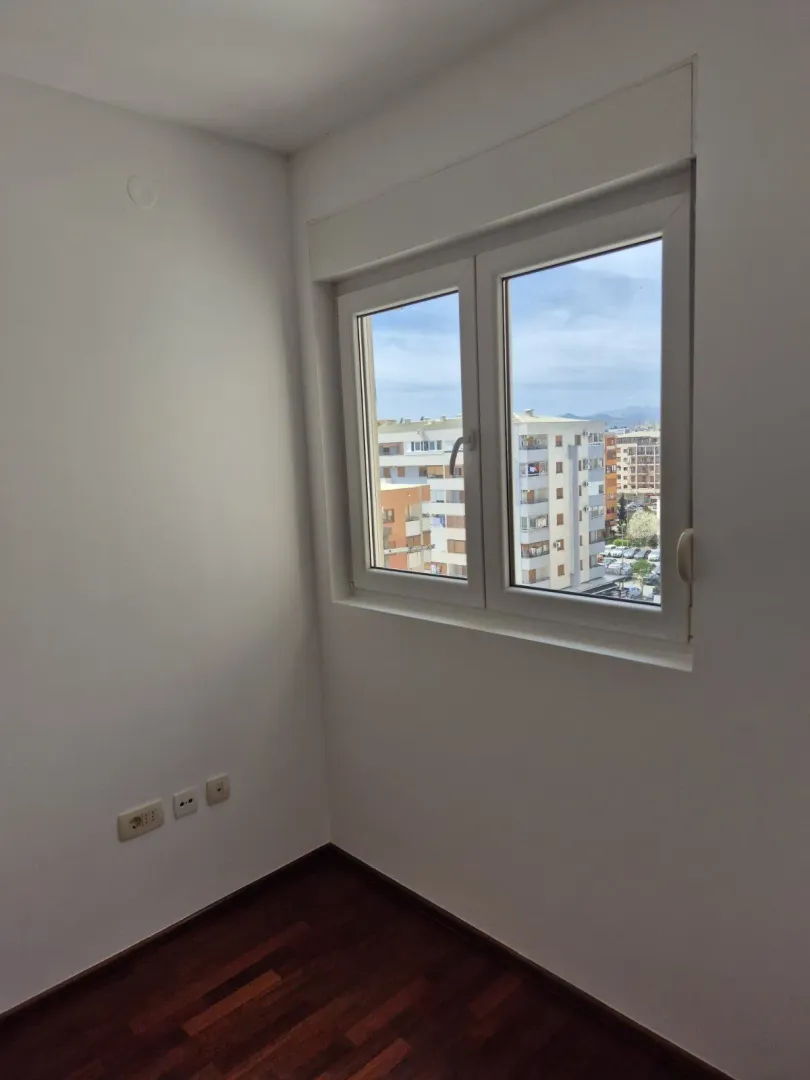 An empty room with a window showing a city view.