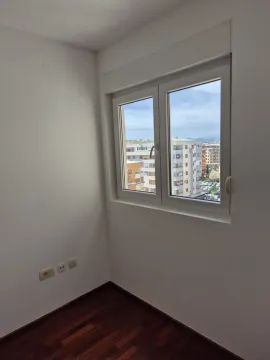 An empty room with a window showing a city view. - image 10