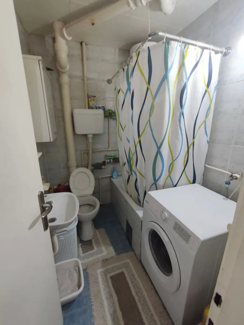 Manje kupatilo sa kadom, umivaonikom, wc šoljom i veš mašinom.
