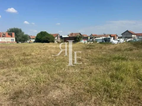 Pogled na ravno građevinsko zemljište obraslo travom sa kućama u pozadini. - image 7