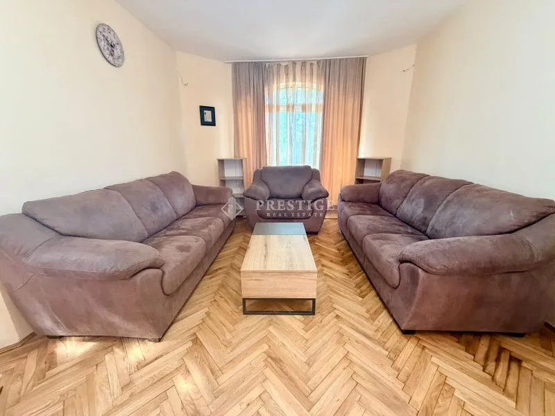 Spacious living room with seating set and parquet flooring.