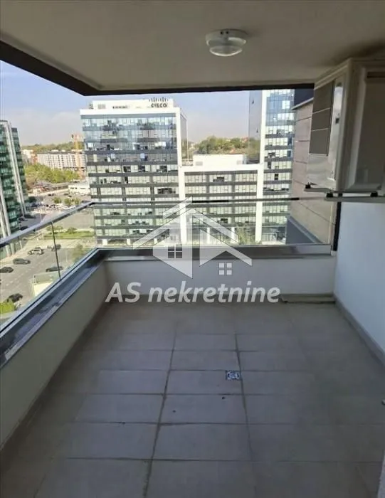 Covered balcony with a glass railing and city views.