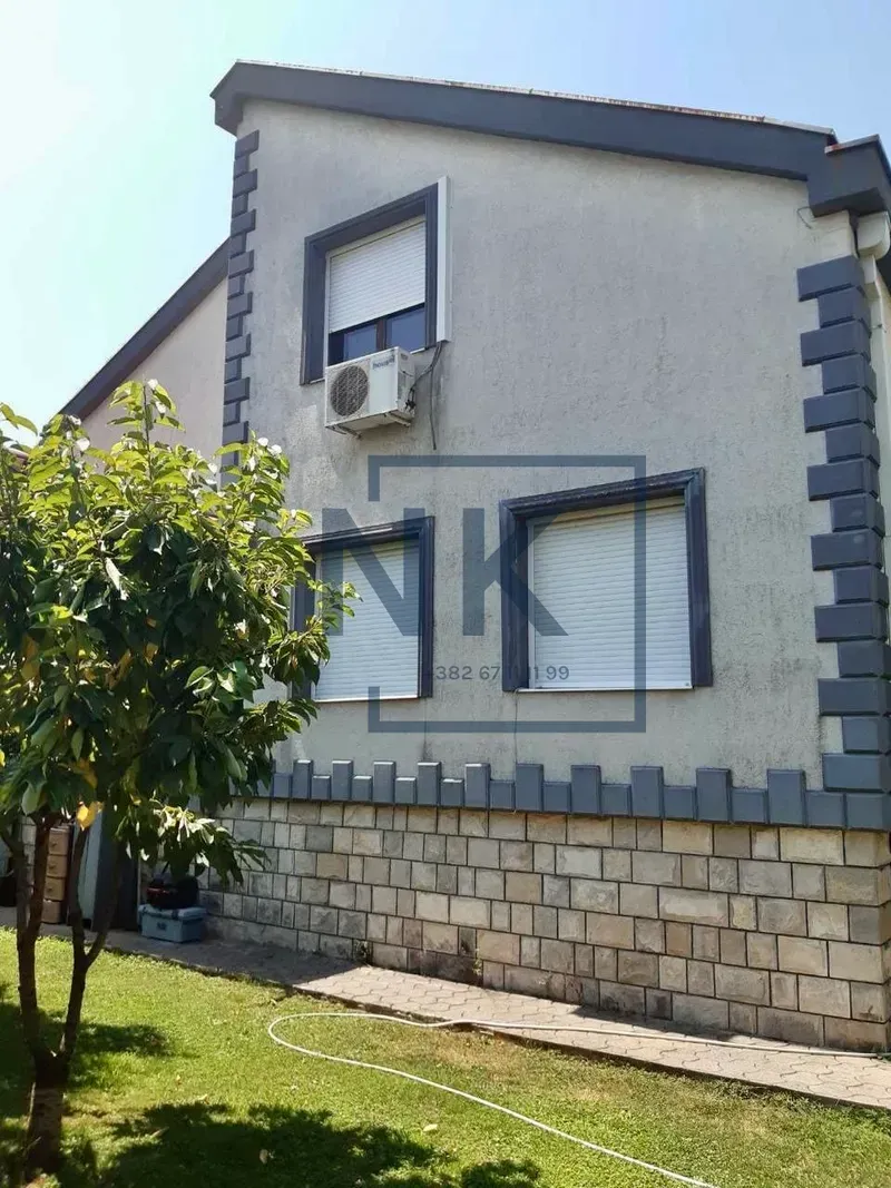 Pogled na spoljašnjost kuće sa uređenim dvorištem i zelenilom.