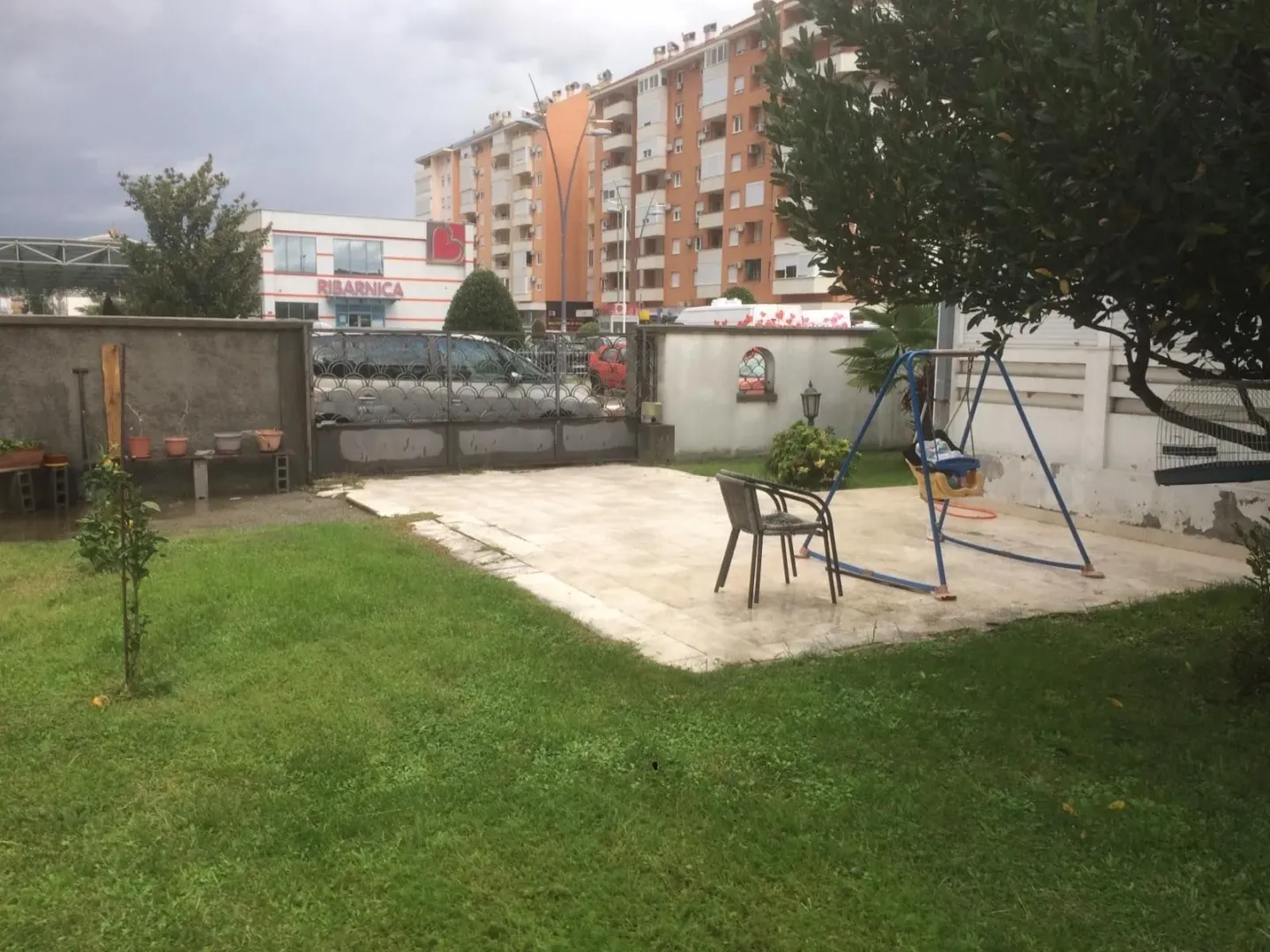 A yard with a lawn, a paved area, and a children's swing.