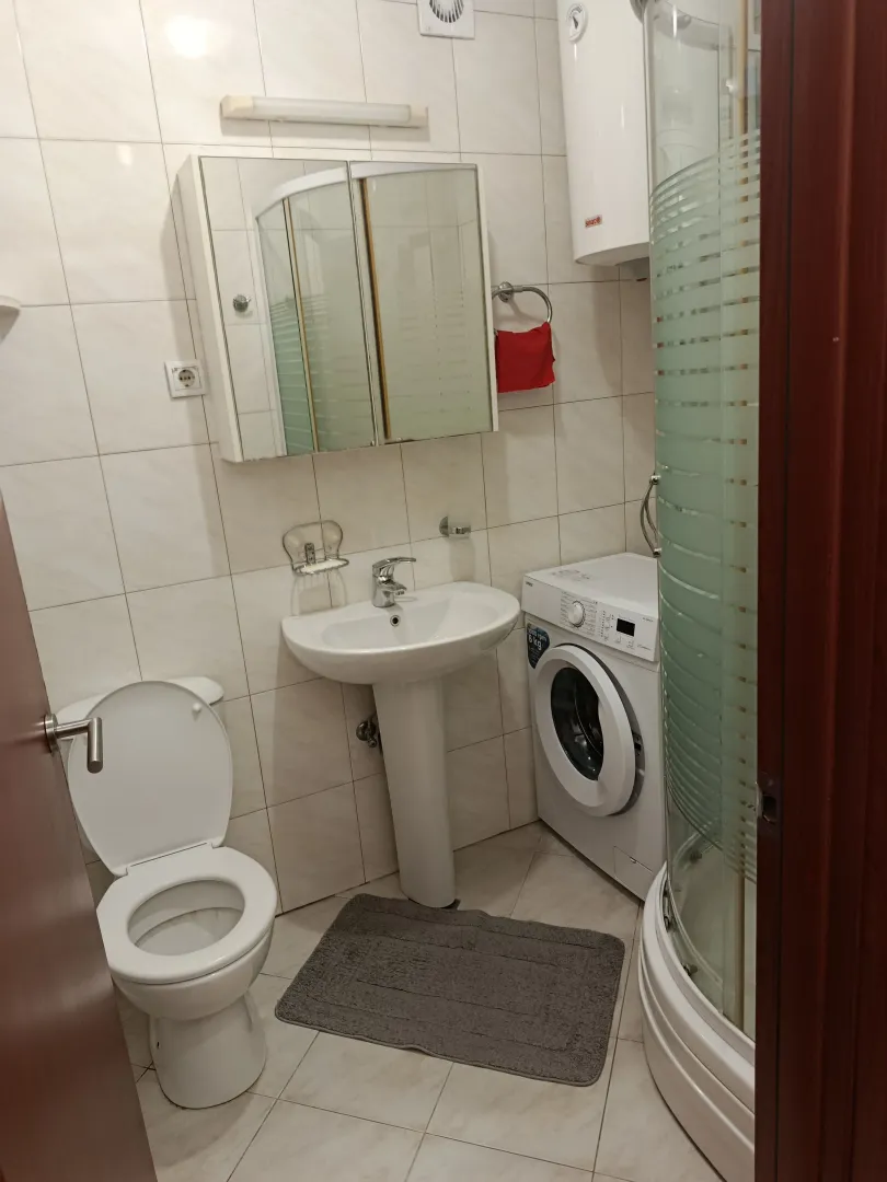Small bathroom equipped with sanitary facilities, a shower cabin, and a washing machine.