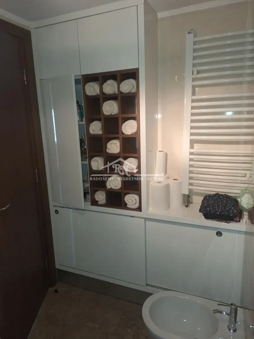 Kupatilo sa ugradnim ormarićem za peškire i sanitarijama.