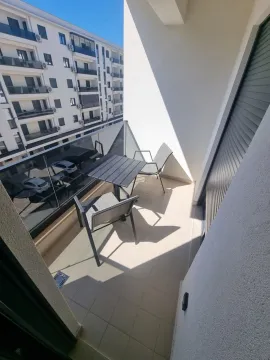 Namješten balkon sa stolom i stolicama i pogledom na okolne zgrade. - image 12