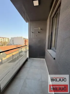 Nenamesteni balkon sa staklenom ogradom i pogledom na okolne zgrade. - image 7