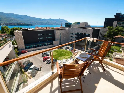 Balcony with a wooden table and chairs overlooking the city and the sea. - image 3