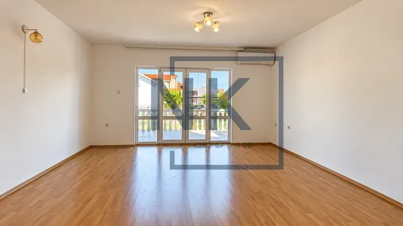 Empty living room with wooden flooring and access to the terrace.
