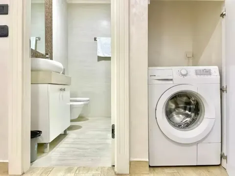 Pogled na kupatilo sa umivaonikom i wc šoljom, pored kojeg se nalazi mašina za veš u niši. - image 10