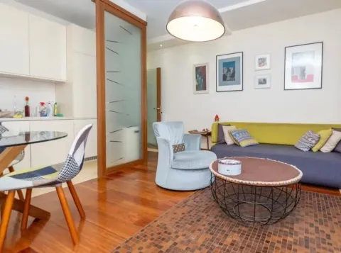 Living room with sofa, armchair, coffee table, and dining area in the background. - image 2