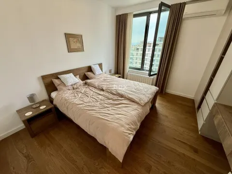 Furnished bedroom with a double bed, wooden flooring, and a window overlooking the city. - image 10