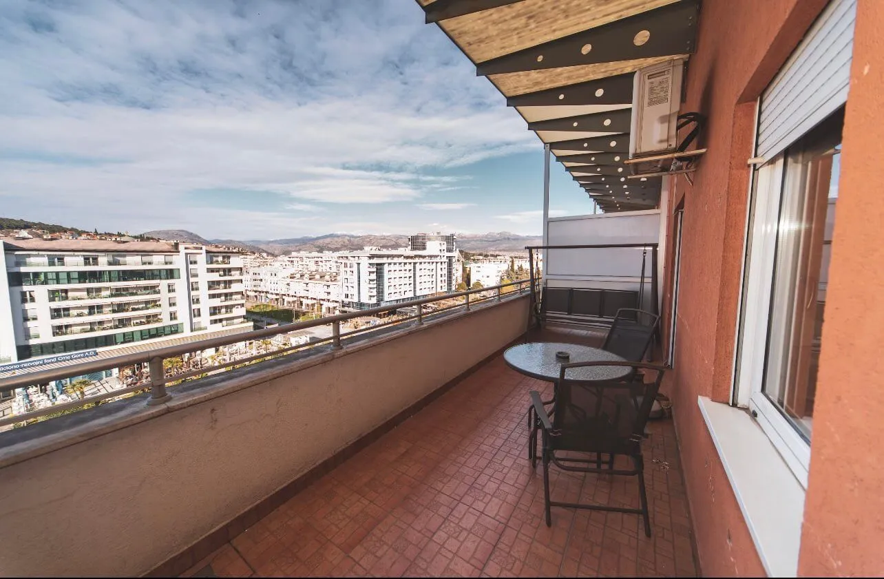 Long covered balcony with outdoor seating and a city view.
