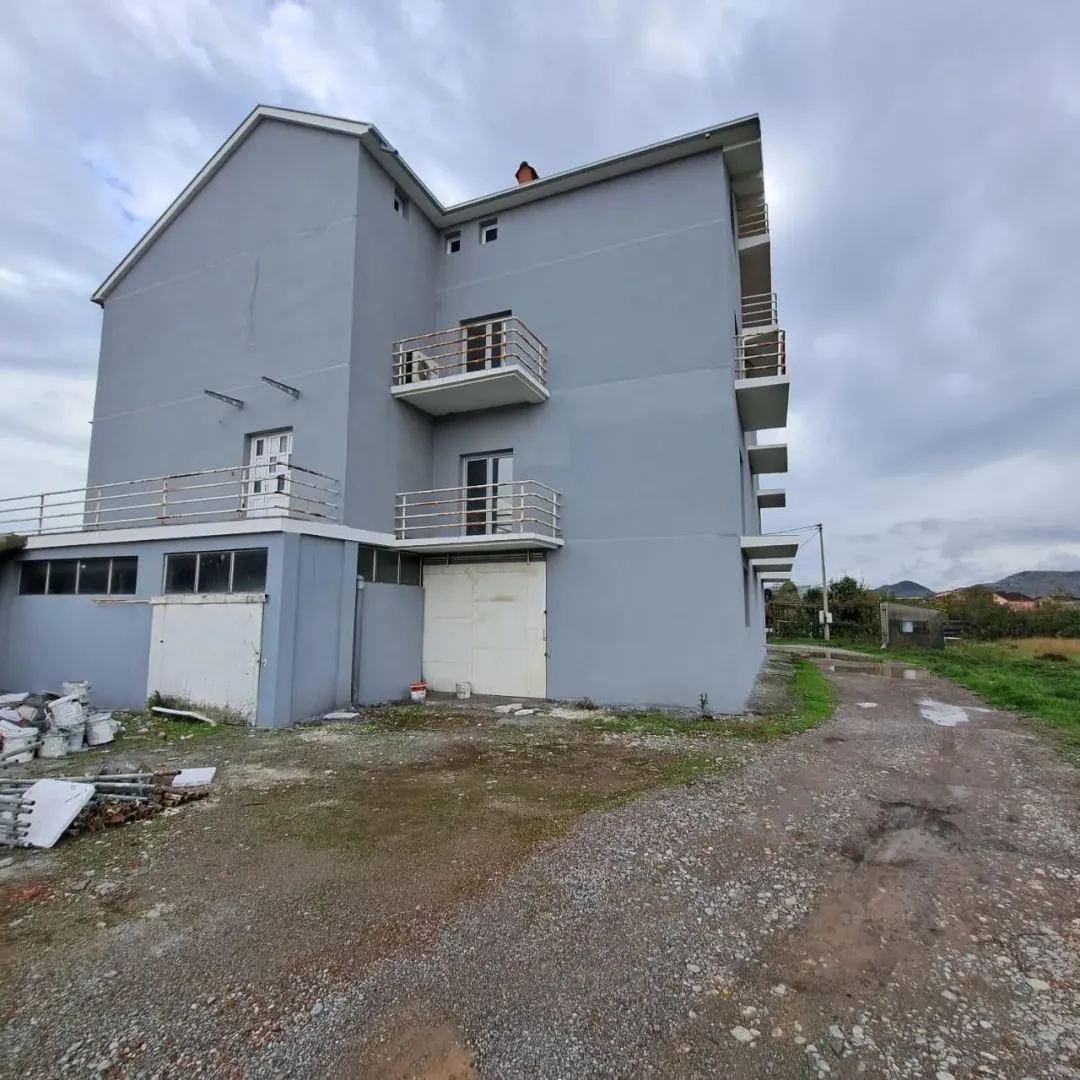 Spoljašnjost višespratne zgrade sa sivom fasadom i balkonima.
