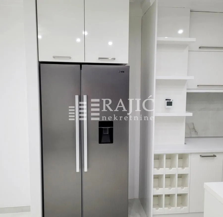 Modern kitchen with white cabinetry and a large refrigerator.