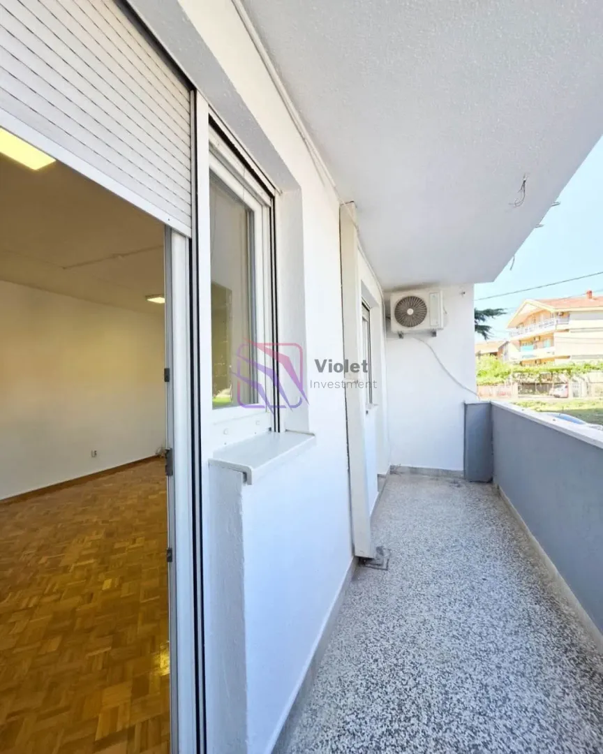 Long covered balcony with a view of surrounding buildings and greenery.