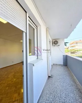 Long covered balcony with a view of surrounding buildings and greenery. - image 8