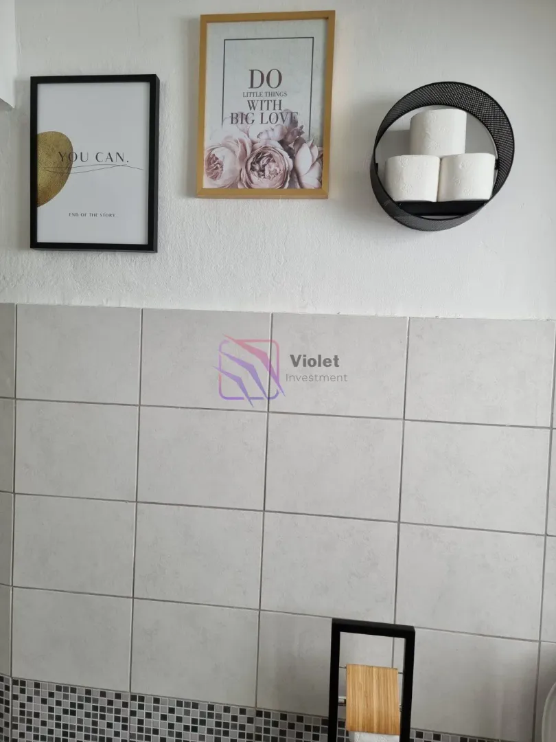 Detail of wall decoration and tiles in the bathroom with a toilet paper holder.