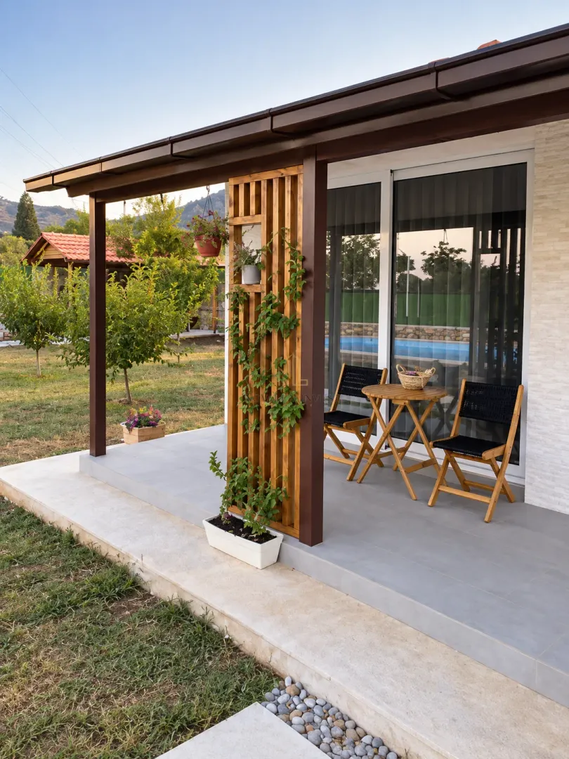 Covered terrace with a wooden table and chairs in front of the house entrance.