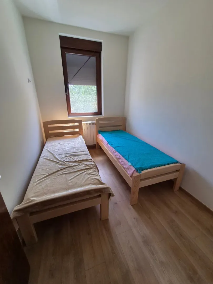 Manja spavaća soba sa dva drvena kreveta na sprat i prozorom.