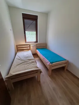 Manja spavaća soba sa dva drvena kreveta na sprat i prozorom. - image 10