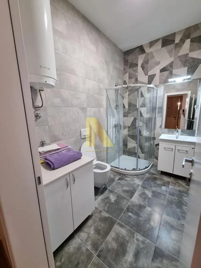 Moderno kupatilo sa tuš kabinom, umivaonikom i bojlerom.