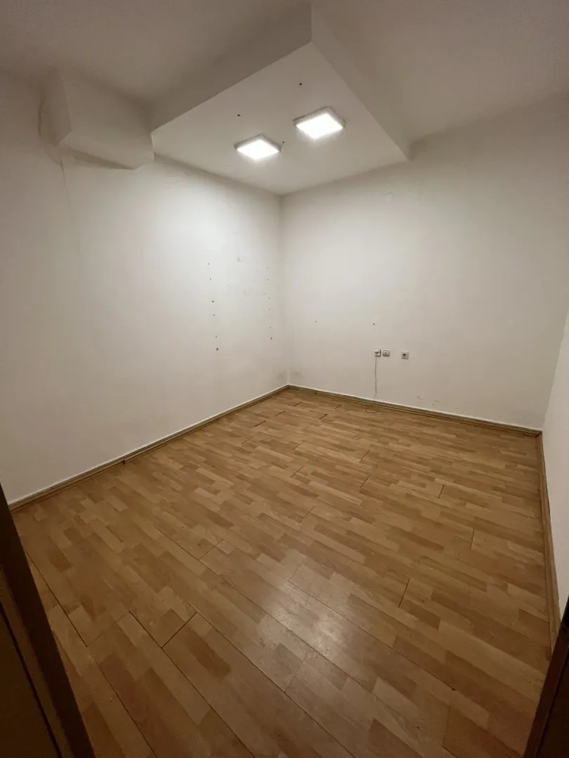 An empty room with laminate flooring and light walls.