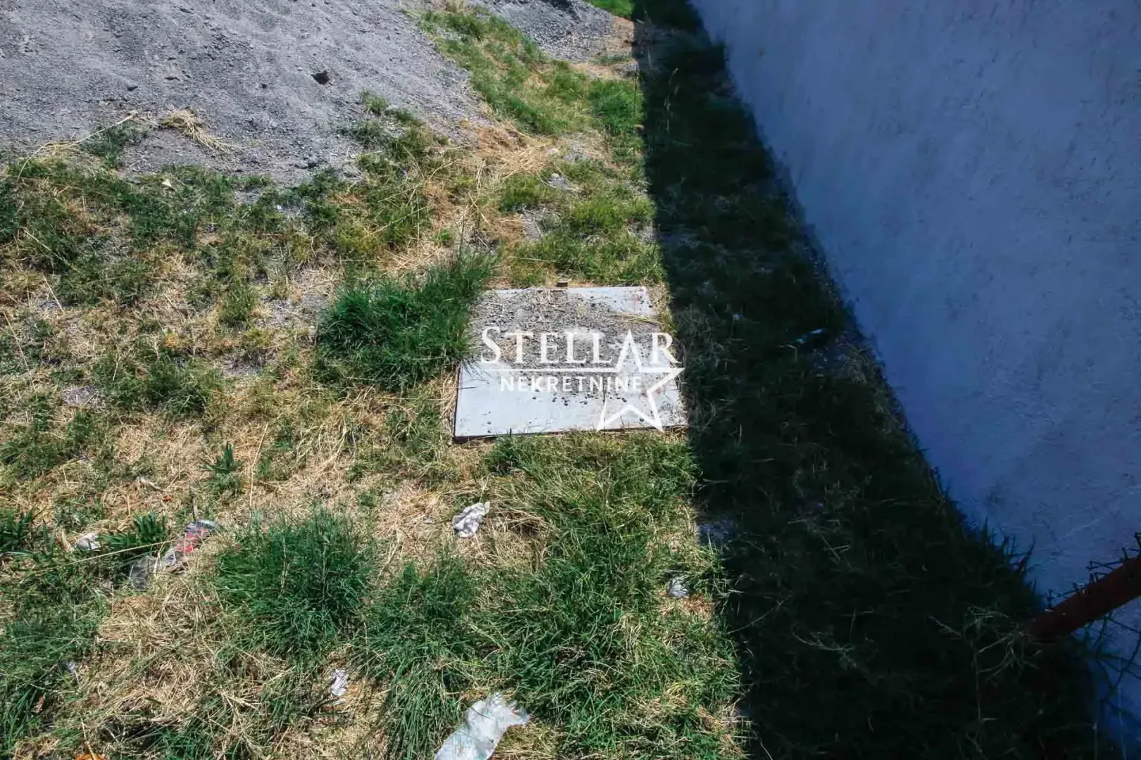 Pogled na dvorište i travnatu površinu pored zgrade.