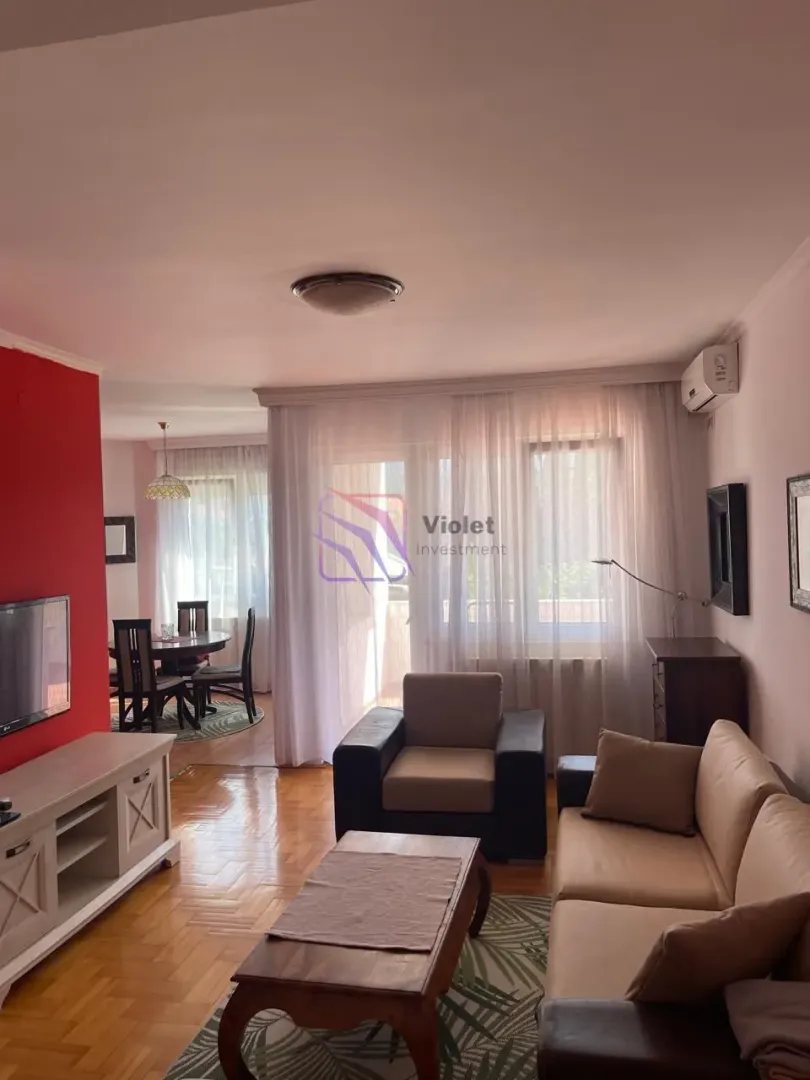 Living room with sofa set, TV unit, and dining area in the background.