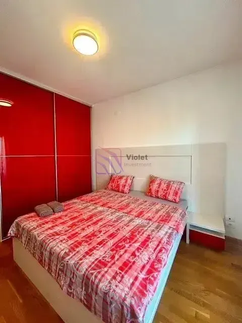 Furnished bedroom with a double bed and a built-in wardrobe with red doors.