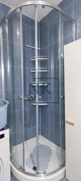 Kabina za tuširanje sa staklenim vratima i plavim zidnim pločicama u kupatilu. - image 3
