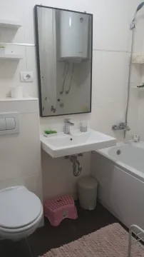 A simple bathroom with a bathtub, sink, and toilet. - image 15