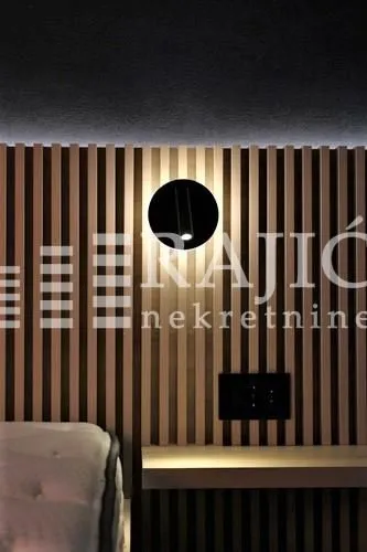 Modern bedroom interior with wooden wall panels and built-in lighting.