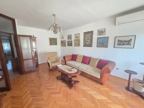 Prostrana dnevna soba sa garniturom, drvenim parketom i umjetničkim slikama na zidu. - image 2
